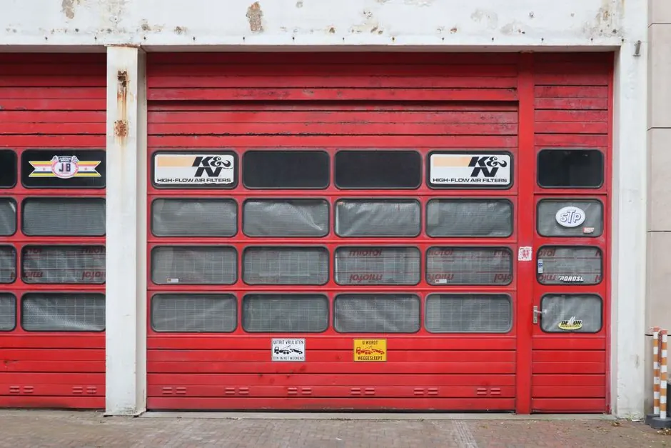 Red industrial garage doors with signage in Nederland, showcasing automotive décor.